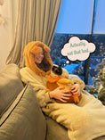 Load image into Gallery viewer, Woman lounging in a comfy wearable blanket hoodie with cat pocket, enjoying a cozy day at home.
